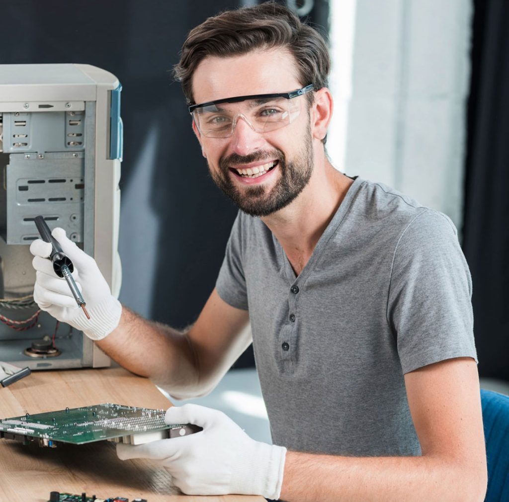 Smiling man repairing a computer motherboard.